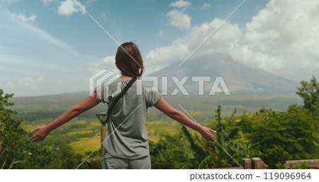 Young woman is embracing the breathtaking beauty of a tropical landscape, with the majestic mayon volcano standing tall in the distance 119096964
