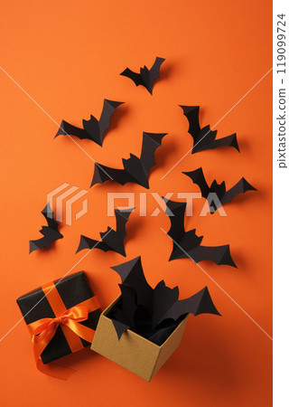 Paper bats flying out of gift box on orange backdrop. Background for Halloween cards, banners, invitations. 119099724