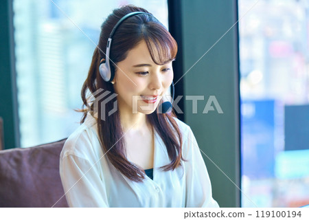 戴著耳機在辦公室的年輕女操作員 戴著耳機在辦公室的年輕女操作員 119100194
