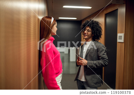 Two young people talking in the corridor and looking involved Two young people talking in the corridor and looking involved 119100378