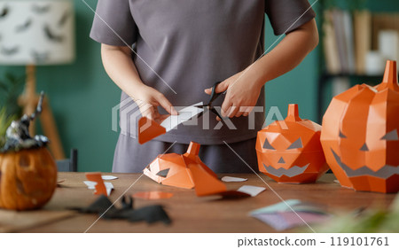 Woman is making Halloween paper pumpkins. 119101761