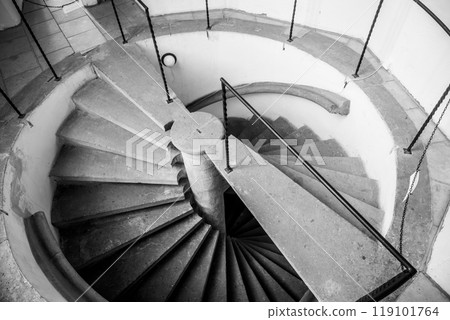 A unique double helix staircase spirals gracefully, showcasing its intricate design. The stone steps and railings create an inviting atmosphere in the interior space. A unique double helix staircase spirals gracefully, showcasing its intricate design. The stone steps and railings create an inviting atmosphere in the interior space. 119101764