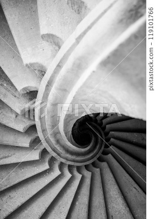 The striking helical staircase showcases a fluid design, winding gracefully upwards with smooth concrete steps. The monochrome tones emphasize its artistic architecture and form. The striking helical staircase showcases a fluid design, winding gracefully upwards with smooth concrete steps. The monochrome tones emphasize its artistic architecture and form. 119101766