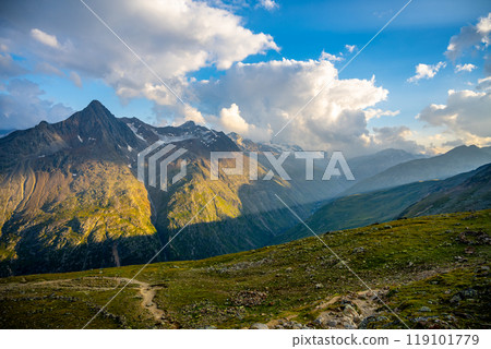 As the sun sets behind the towering peaks of the Otztal Alps, the landscape glows with warm colors. Shadows stretch across the valleys, highlighting the natural beauty of this Alpine paradise. As the sun sets behind the towering peaks of the Otztal Alps, the landscape glows with warm colors. Shadows stretch across the valleys, highlighting the natural beauty of this Alpine paradise. 119101779