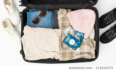 Travel background. Open Suitcase with summer cloth, hat, passports on the cloth background. High quality photo. Woman's hands packing suitcase for a journey on the white background. Travel 119102072