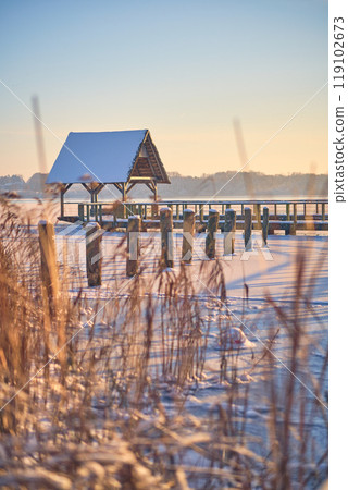Hut on frozen lake in Hemmelsdorf, northern Germany 119102673