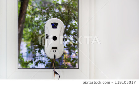 Robot window cleaner washes glass against foliage background Robot window cleaner washes glass against foliage background 119103017