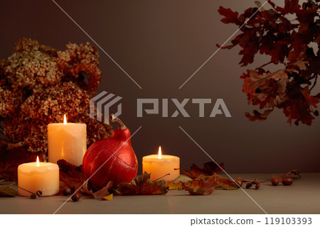 Still life with pumpkin, dried-up leaves, and burning candles. 119103393