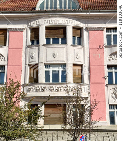 Ornate details of a historic building facade illuminated by sunlight. the intricate architectural elements and pastel colors highlight the building's elegance and charm 119103646