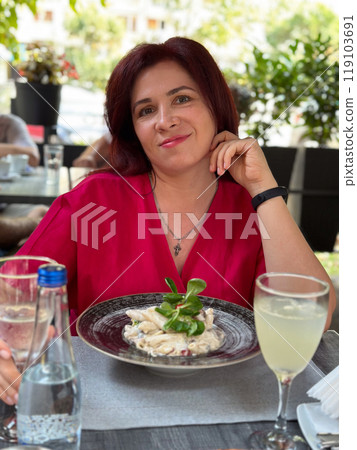 Woman enjoying a refreshing drink at an outdoor cafe in a vibrant setting. Relaxation and the joy of savoring a leisurely afternoon Woman enjoying a refreshing drink at an outdoor cafe in a vibrant setting. Relaxation and the joy of savoring a leisurely afternoon 119103691