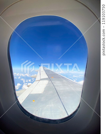 View of airplane wing through window at high altitude, showcasing clear blue sky and clouds far below. Serene beauty of flight and the expansive view of the horizon from above. Beauty of aerial views View of airplane wing through window at high altitude, showcasing clear blue sky and clouds far below. Serene beauty of flight and the expansive view of the horizon from above. Beauty of aerial views 119103750