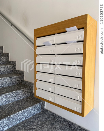 Row of mailboxes in a modern apartment building, with letters sticking out, symbolizing communication and daily life. Blend of functionality and design, capturing the essence of urban living Row of mailboxes in a modern apartment building, with letters sticking out, symbolizing communication and daily life. Blend of functionality and design, capturing the essence of urban living 119103758