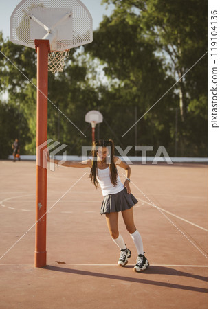 A Young Girl Having Fun While Playing Basketball on a Bright and Sunny Day Outside 119104136