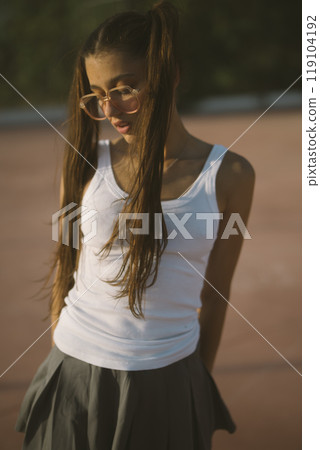 A Youthful Girl is Posing Confidently in Casual Summer Attire with a Cheerful Smile A Youthful Girl is Posing Confidently in Casual Summer Attire with a Cheerful Smile 119104192