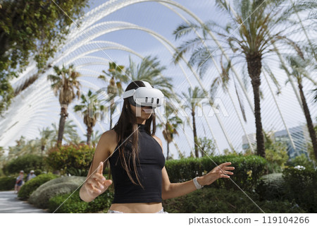 A woman engaging in the exciting world of virtual reality while enjoying an outdoor setting 119104266