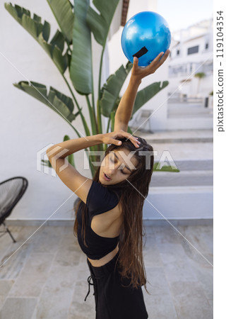 A Stylish Model is Posing Gracefully with a Blue Ball in a Trendy, Modern Setting 119104354