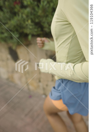 A woman is jogging outdoors while dressed in comfortable and stylish sportswear attire 119104366