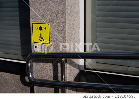 Hand rails to assist person in wheelchair next to handicap sign on wall and call button to assist person with disability, modern entrance to building with convenient ramp for people with disabilities Hand rails to assist person in wheelchair next to handicap sign on wall and call button to assist person with disability, modern entrance to building with convenient ramp for people with disabilities 119104553