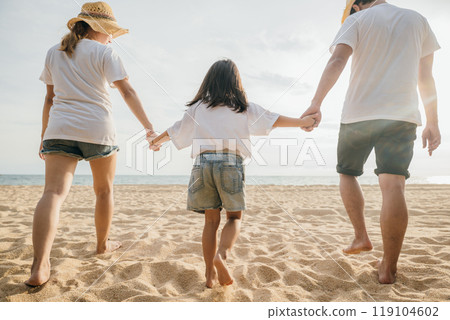 Happy Asian parents with their daughters enjoying playful at beach. Little girls with their mother and father holding hand of child walking on sand beach. Positive family outdoor activity 119104602