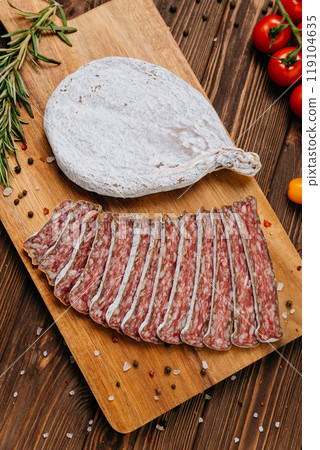 Dry-cured salami on board, ideal for rustic charcuterie presentations and gourmet food styling 119104635