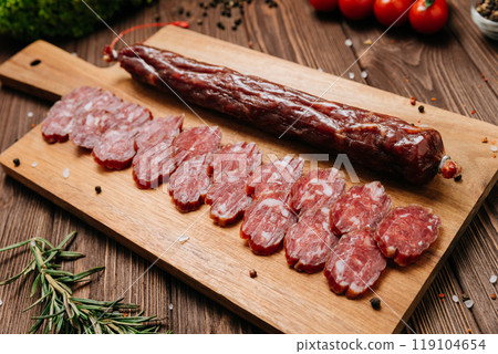 Smoked salami sticks on a wooden board with herbs, perfect for charcuterie boards and gourmet snacks Smoked salami sticks on a wooden board with herbs, perfect for charcuterie boards and gourmet snacks 119104654