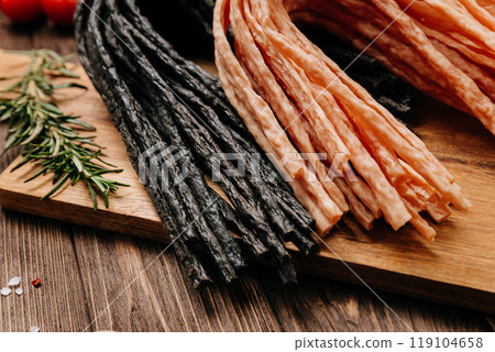 Variety of black and light meat sticks on board with herbs and spices, ideal for culinary display 119104658