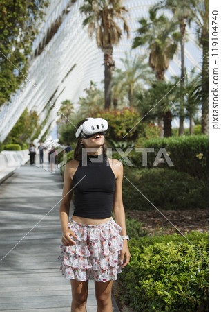 A young woman is immersed in a captivating virtual reality experience in a tropical paradise A young woman is immersed in a captivating virtual reality experience in a tropical paradise 119104740