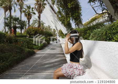 A Woman Delightfully Enjoying an Immersive Virtual Reality Experience in a Relaxing Outdoor Setting A Woman Delightfully Enjoying an Immersive Virtual Reality Experience in a Relaxing Outdoor Setting 119104800