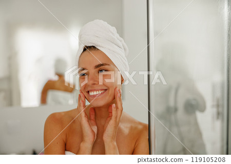 A Radiant Woman Enjoys Her Skincare Routine After a Refreshing Shower While Wrapped in a Towel A Radiant Woman Enjoys Her Skincare Routine After a Refreshing Shower While Wrapped in a Towel 119105208