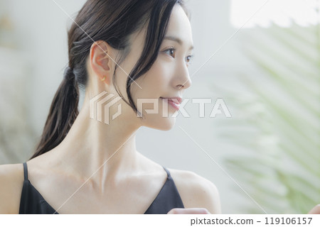 A woman in a black camisole dress standing by the window 119106157