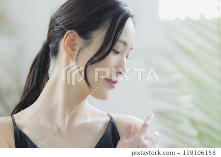 A woman in a black camisole dress standing by the window 119106158