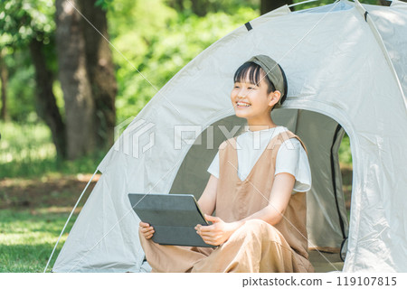 Girl using a tablet in a tent at a campsite/leisure facility Girl using a tablet in a tent at a campsite/leisure facility 119107815