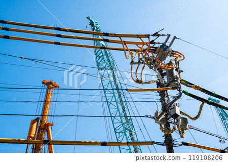 Electric wire protection covers around the construction site and cranes stretching into the blue sky a-1 Electric wire protection covers around the construction site and cranes stretching into the blue sky a-1 119108206