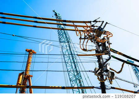 Electric wire protection covers around a construction site and cranes stretching into the blue sky a-2 High saturation contrast 119108207