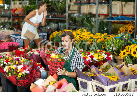 Positive male seller in apron holds designer bouquet in hands 119109538