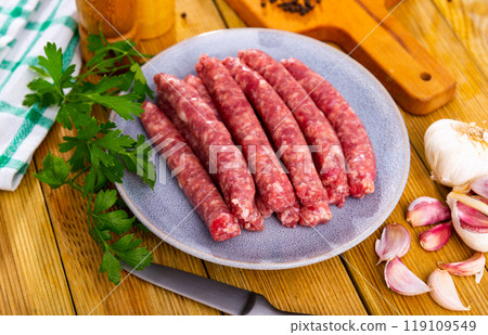 Plate of raw longaniza wit greens, garlic and spices prepared for cooking 119109549