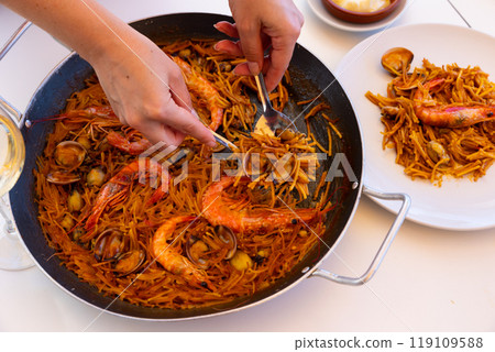 Womens hands lay out sea pasta in plates for family dinner. Womens hands lay out sea pasta in plates for family dinner. 119109588