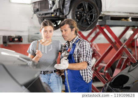 Male car repair shop worker consulting female client Male car repair shop worker consulting female client 119109628