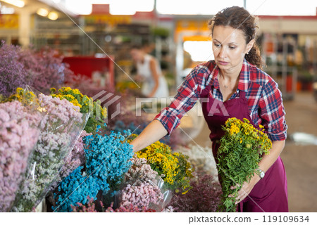 Adult female seller holding bouquet of dried flowers 119109634