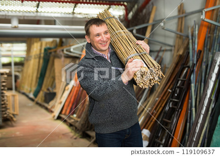 Man chooses decorative fence from bamboo in store Man chooses decorative fence from bamboo in store 119109637