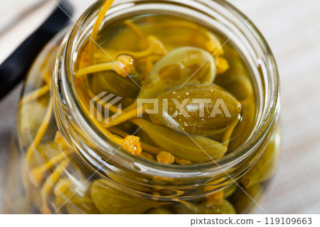 Pickled capers in glass jar on wooden table 119109663