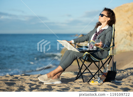 Business woman sitting with laptop and whiskey by ocean Business woman sitting with laptop and whiskey by ocean 119109722