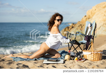 Curvy brown haired woman in shirt and tie on beach 119109764