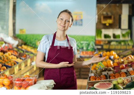 Portrait of saleswoman posing at grocery store. Invites you to go shopping Portrait of saleswoman posing at grocery store. Invites you to go shopping 119109823