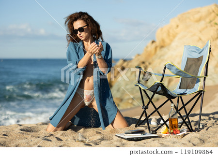 Businesswoman topless in jacket poses on sea beach 119109864