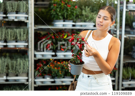 Young girl holding pepper in flower-pot in plants market 119109889