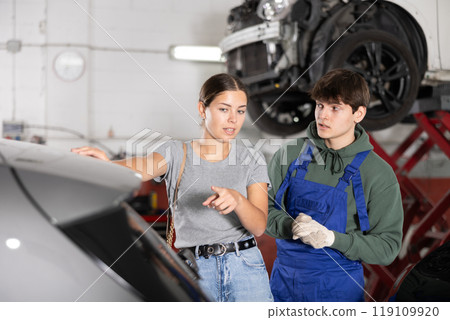 Interested female customer discussing car repairs with mechanic 119109920
