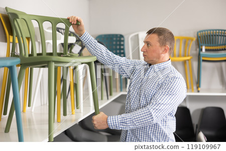 In furniture store, man considering choose chairs for completing office suite 119109967
