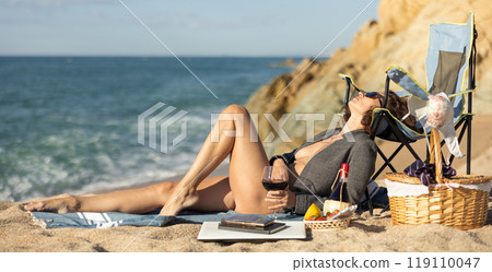 Sexy businesswoman posing naked with picnic basket on seashore on day Sexy businesswoman posing naked with picnic basket on seashore on day 119110047