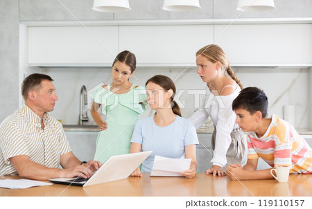 Man with laptop does remote work, frustrated wife reads letter, and alarmed children stand nearby 119110157
